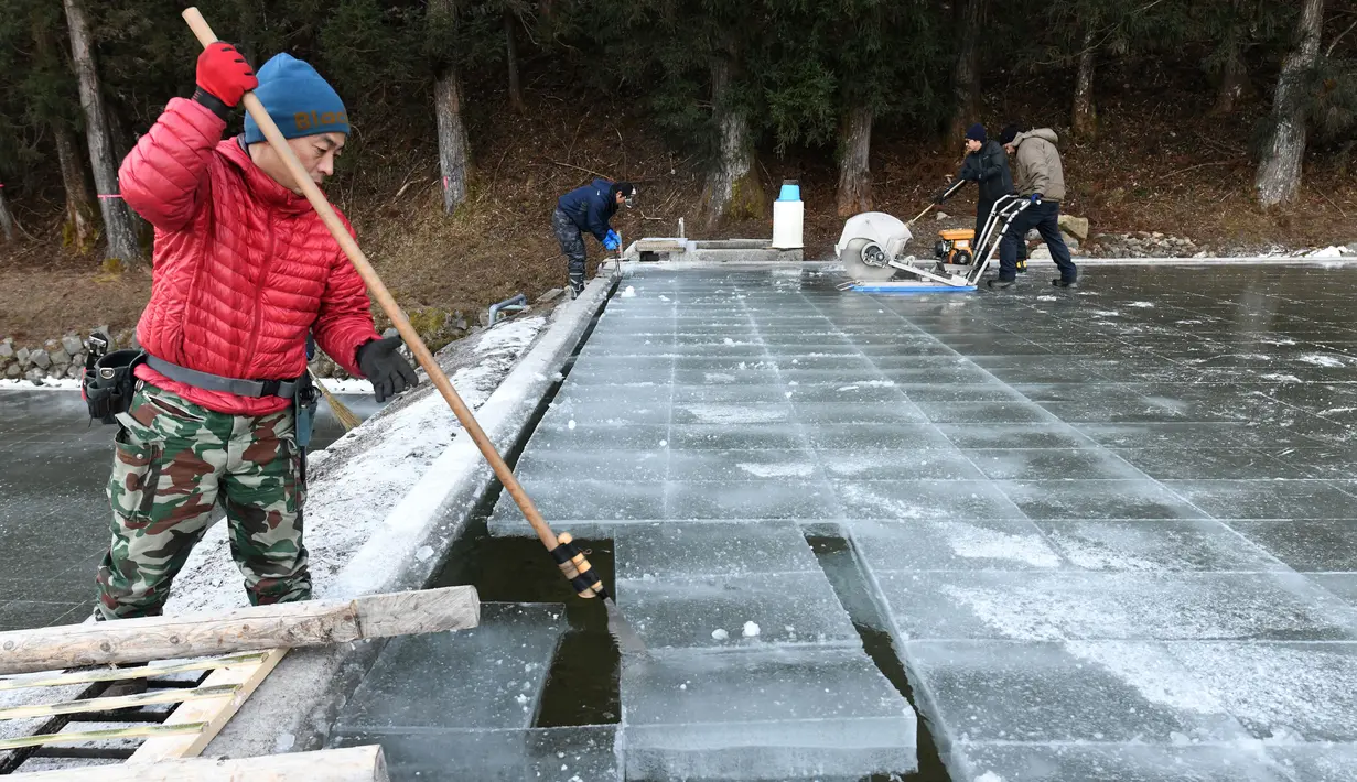 Seorang pekerja mengeluarkan balok es alami untuk membuat kakigori atau es serutsetelah dipotong dari kolam udara terbuka di sebuah pabrik di Nikko, Prefektur Tochigi (10/1/2019). (AFP Photo/Toshifumi Kitamura)