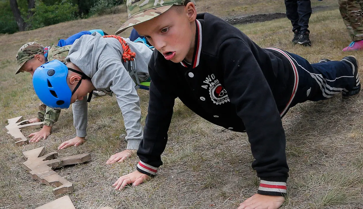 Siswa melakukan push-up saat mengikuti pelatihan di kamp paramiliter di Kiev, Ukraina, (14/7). Konflik yang terjadi di bagian timur Ukraina membuat beberapa orang tua sangat ingin memastikan anak-anak mereka siap jika perang. (AP Photo/Efrem Lukatsky)