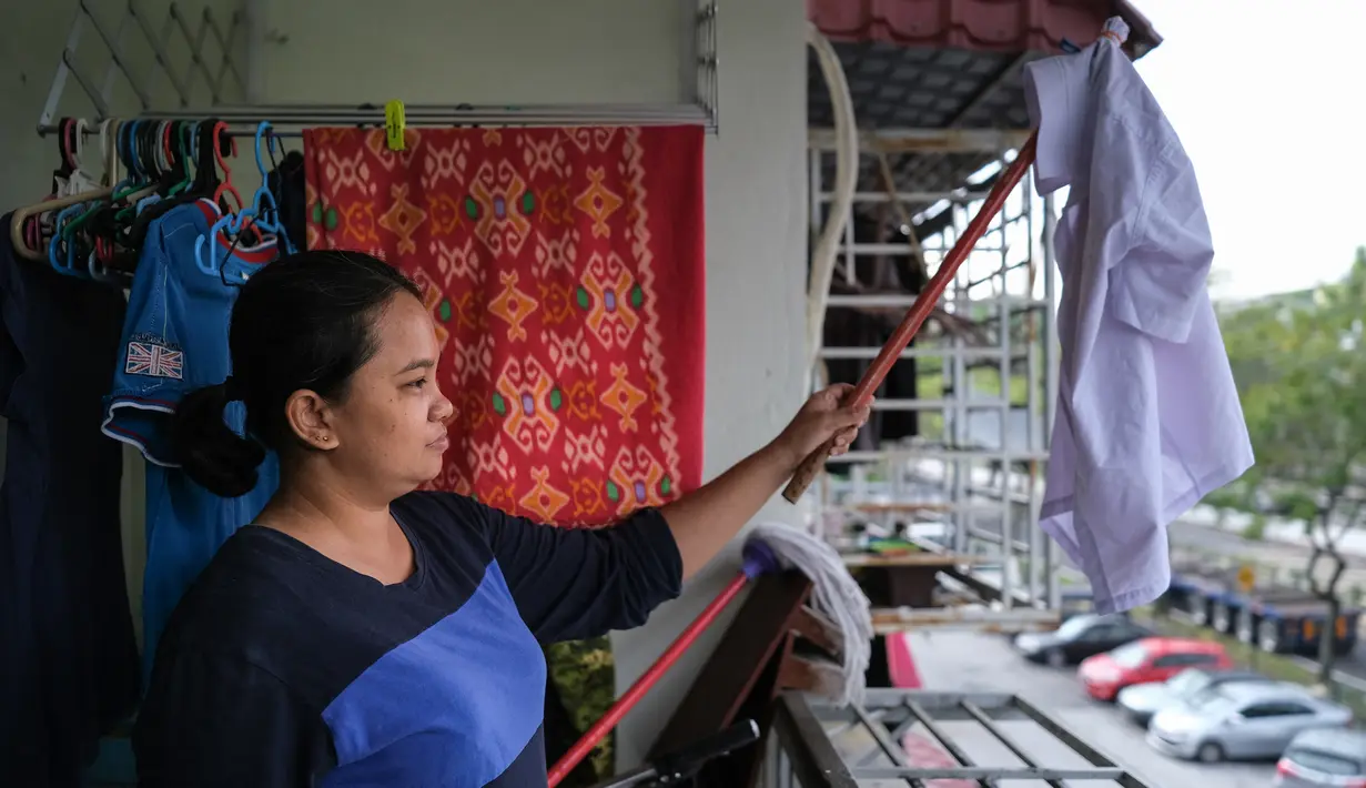 Ibu tunggal Tilda Kalaivani melambaikan kemeja yang digunakan sebagai bendera putih di apartemen sewaannya di Kuala Lumpur pada 6 Juli 2021. Akibat lockdown nasional, banyak keluarga berpenghasilan rendah yang terdampak oleh pandemi COVID-19 semakin kesulitan dalam menjalani hidup. (Mohd RASFAN/AFP)