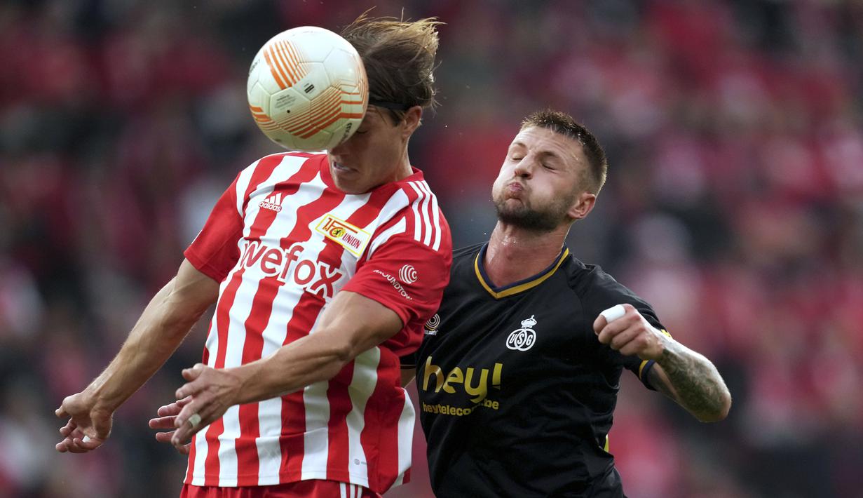 Pemain FC Union Berlin, Kevin Behrens (kiri) duel udara dengan pemain Royale Union Saint-Gilloise, Siebe Van Der Heyden pada laga Liga Europa di Berlin, Jumat (9/9/2022). (AP/Michael Sohn)