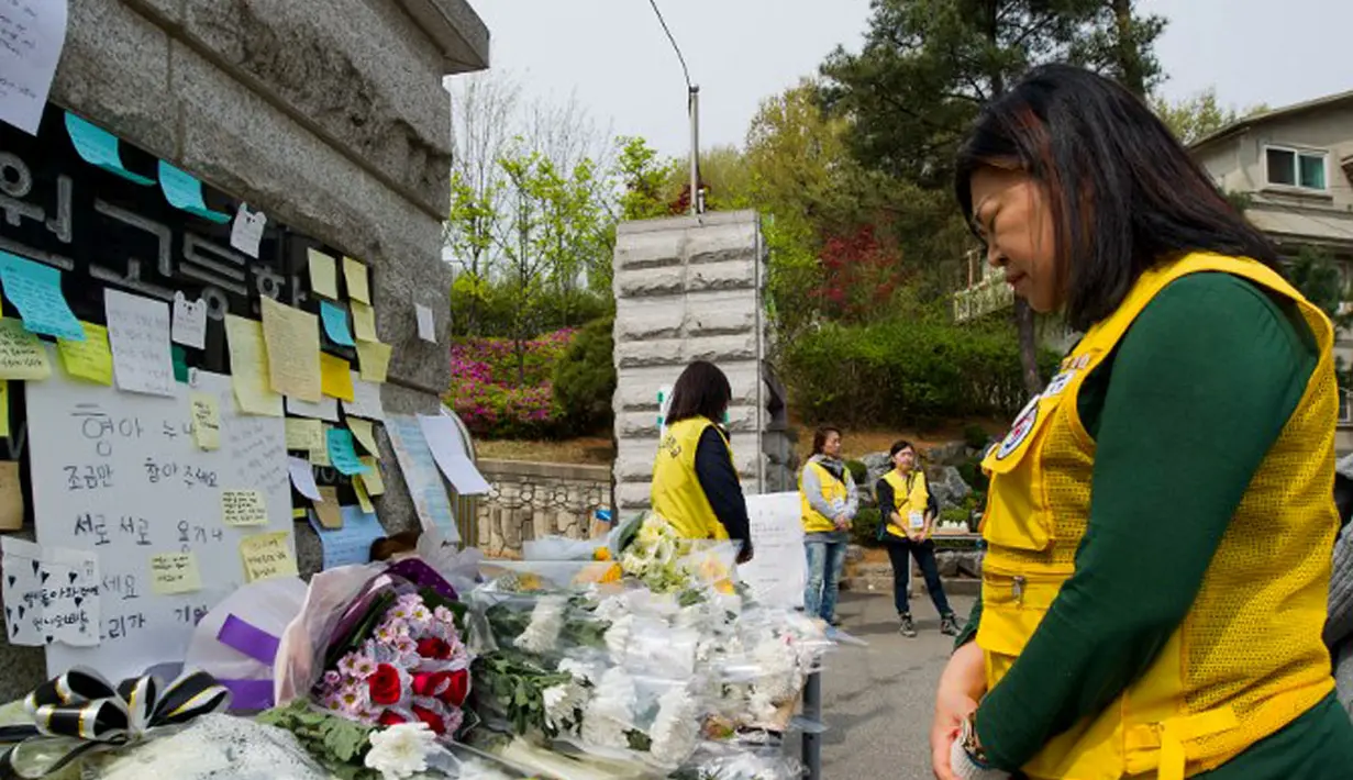 Seorang wanita berdoa di depan pesan dan karangan bunga yang diletakkan untuk mengenang para korban tenggelamnya kapal feri Sewol, Senin (21/4/2014). (AFP PHOTO/KIM DOO-HO)