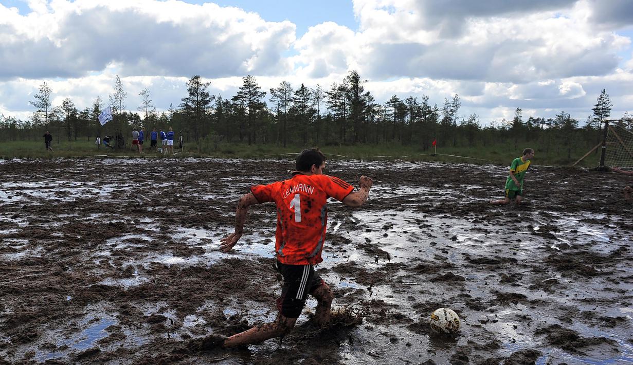 Seorang peserta dari Rusia menendang bola diatas lumpur pada ajang Rusia Swamp Football Cup di Saint Petersburg, (9/7/2016). (AFP/STR)