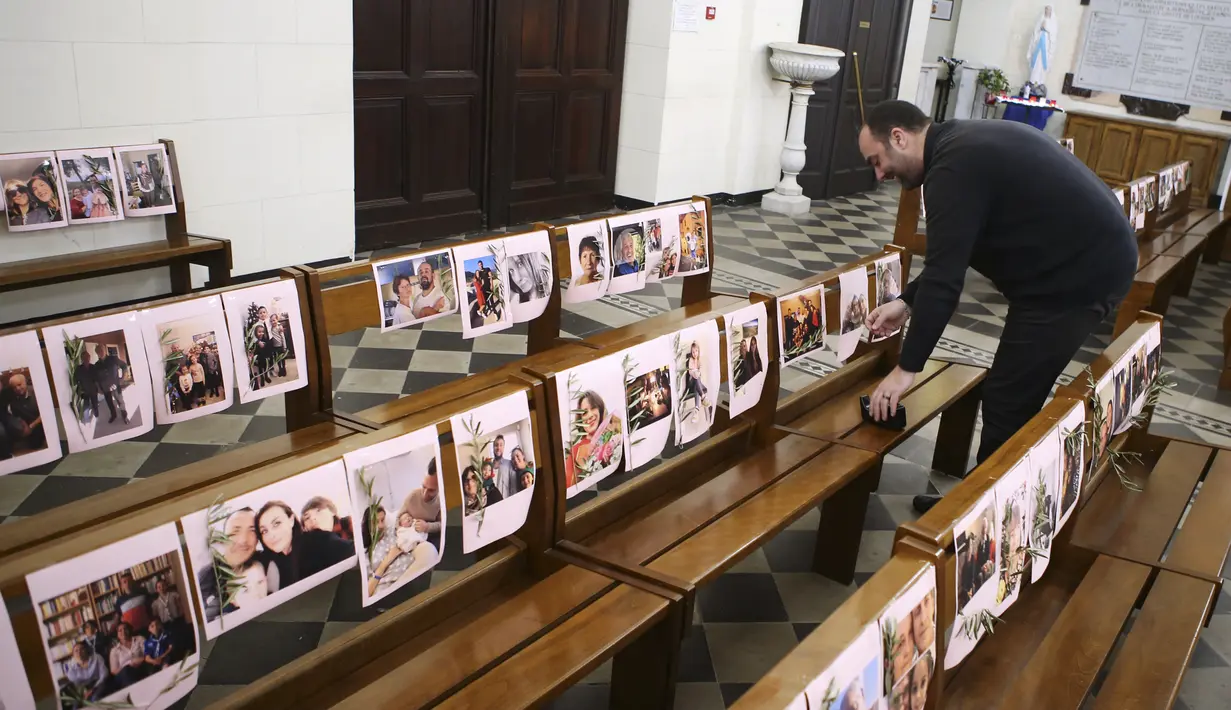 Pastor Katolik Georges Nicoli menempelkan foto jemaat sebelum merayakan misa Kamis Putih yang  disiarkan langsung di Facebook di gereja Notre Dame De Lourdes di Bastia, di pulau Korsika Mediterania, Prancis (9/4/2020). (AFP/Pascal Pochard-Casabianca)