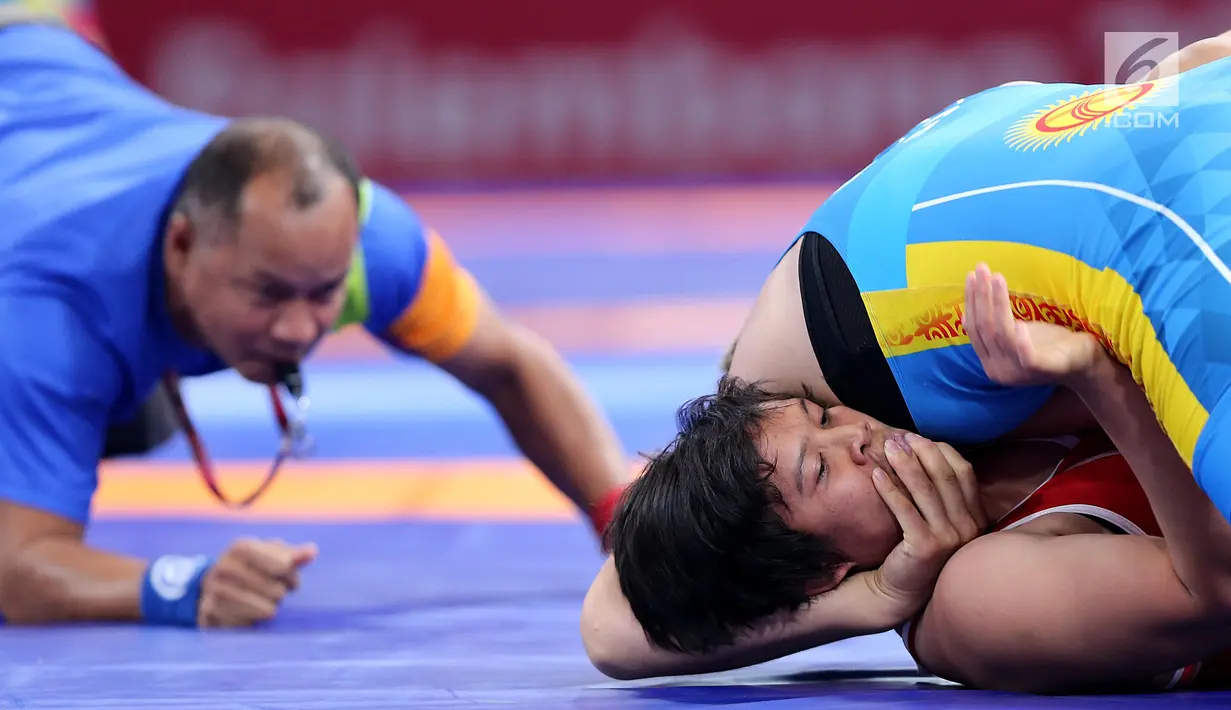 Pegulat Kirgizstan Medet Kyzy Aiperi mengunci pegulat putri Indonesia, Ridwan Ridha Wahyadaniyaty pada kelas putri 76 Kg di JCC Senayan, Selasa (21/8). Pada perdelapan final, Ridha kalah atas lawanya dengan skor 0-12. (Liputan6.com/Fery Pradolo)