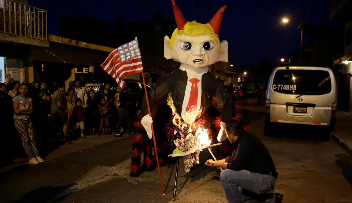 Seorang pria menyiapkan pembakaran pinata karakter Donald Trump saat perayaan tradisional, Pembakaran Iblis di Guatemala City, Guatemala (7/12). Biasanya perayaan ini digelar untuk menyambut natal di daerah Amerika Selatan. (Reuters/Luis Echeverria)