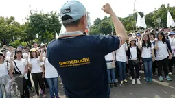 Massa yang tergabung dalam Generasi Muda Buddhis Indonesia (Gemabudhi) melakukan persiapan sebelum membagikan bunga kepada pengguna jalan di depan Istana Negara, Jakarta, Sabtu (6/1). (Liputan6.com/Immanuel Antonius)