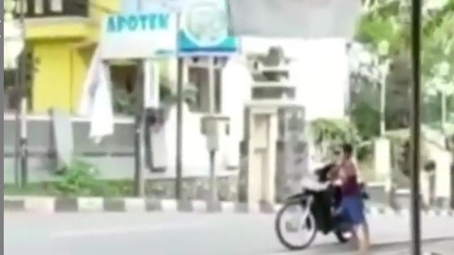 terlihat seorang anak sedang berdiri di samping sebuah kendaraan di pinggir jalan