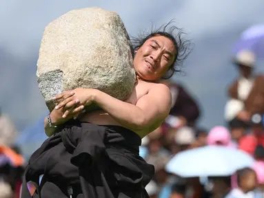 Seorang partisipan mengikuti kompetisi angkat batu yang digelar dalam festival balap kuda Dangjiren di Wilayah Damxung, Daerah Otonom Tibet, China barat daya, pada 11 Agustus 2020. (Xinhua/Purbu Zhaxi)