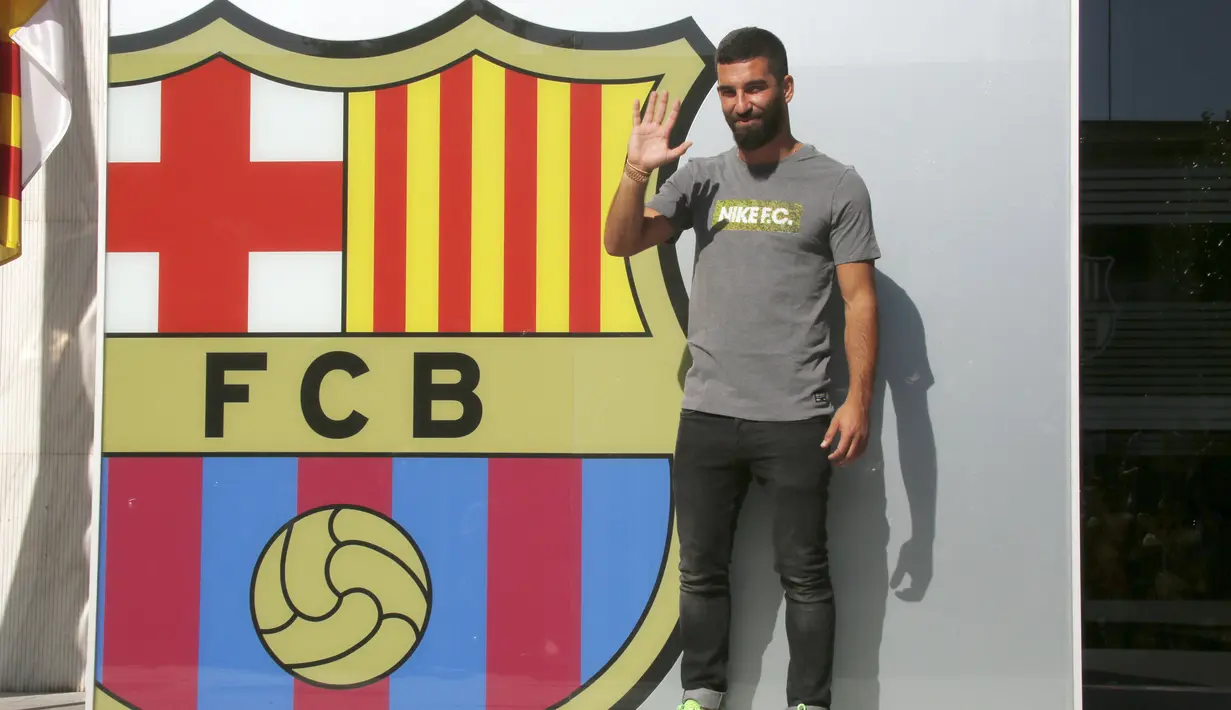 Arda Turan melambaikan tangan ke awak media saat sesi perkenalan di luar Stadion Camp Nou, Barcelona, Spanyol, (9/7/2015). Pemain kelahiran 30 Januari 1987 resmi di kontrak  Barcelona hingga lima tahun ke depan. (AFP PHOTO/Lluis GENE)
