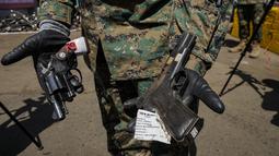 Seorang perwira Angkatan Darat Chile menunjukkan senjata yang secara sukarela diserahkan ke polisi atau disita, sebelum dilebur di Santiago, Chile, Kamis (11/11/2021). Lebih dari 13.600 senjata ilegal dihancurkan, menurut komisi nasional yang mengatur senjata. (AP Photo/Esteban Felix)
