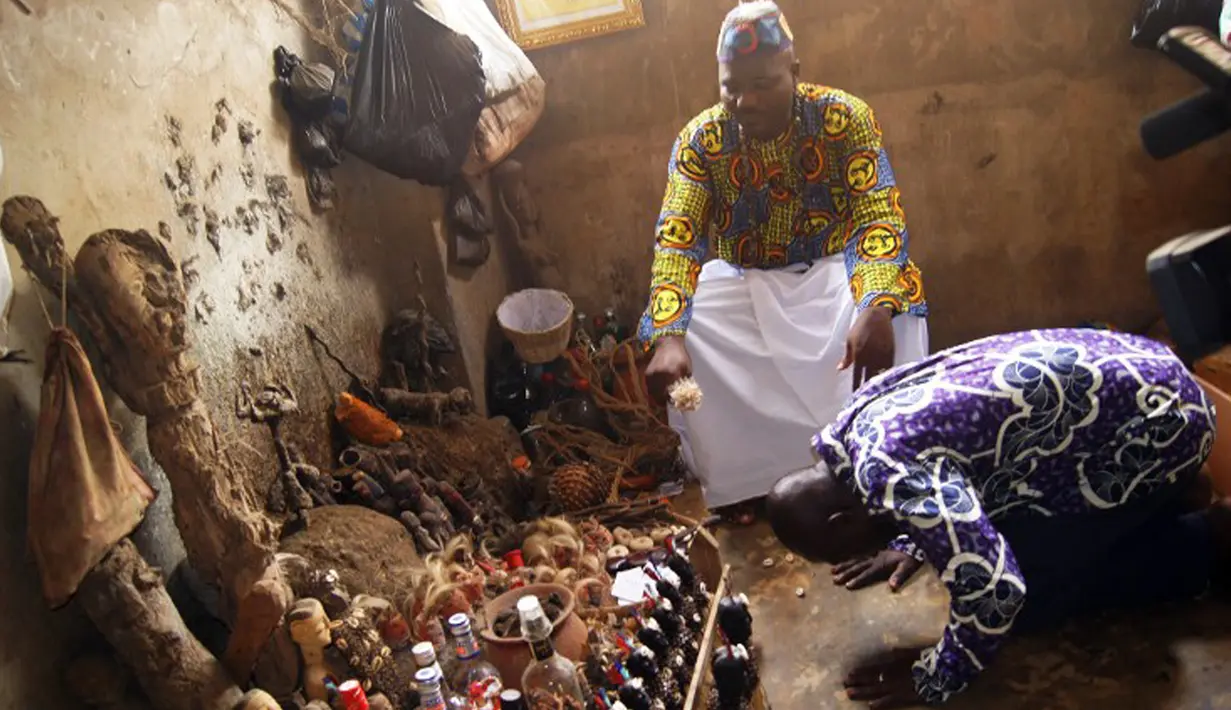 Lucien Yekpon, seorang dukun Lome bersama pasiennya yang sedang membungkuk di depan benda-benda jimat di pasar Akodessewa di Togo, Afrika, 5 Agustus 2015. Pasar ini menjual berbagai benda-benda klenik dan juga peralatan sihir. (AFP PHOTO/EMILE KOUTON) 