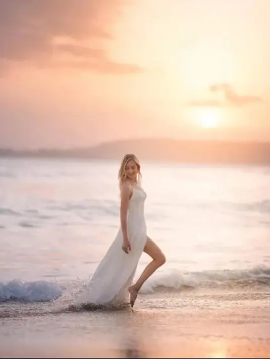 Pinggir pantai, dan matahari menjadi pasangan yang cocok untuk Varsha Strauss Adhikumoro berpose mengenakan gaun putih panjang di pinggir pantai. (Foto: Instagram/varshaadhikumoro)