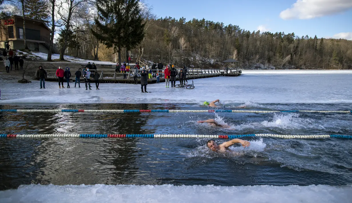 Para perenang bertanding saat kompetisi renang musim dingin di lubang es sepanjang 25 meter di sebuah danau dekat Vilnius, Lithuania, Sabtu (6/3/2021).  Suhu air saat itu 3 derajat Celcius, sedangkan udaranya -3 derajat Celsius. (AP Photo/Mindaugas Kulbis)
