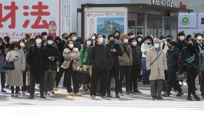 Orang-orang memakai masker untuk melindungi dari penyebaran virus corona menunggu di persimpangan di Tokyo (8/2/2021). Jumlah infeksi virus corona di Ibu Kota Tokyo, Jepang, meningkat sampai sembilan kali lipat sejak akhir musim panas lalu. (AP Photo/Eugene Hoshiko)