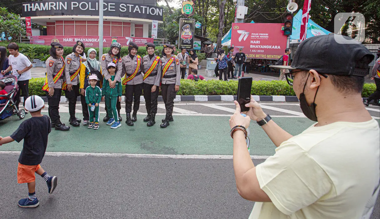 Sejumlah anak berfoto dengan polisi wanita (Polwan) saat Car Free Day (CFD) di Bundaran HI, Jakarta, Minggu (2/7/2023). Masih dalam nuansa memperingati HUT ke-77 Bhayangkara, kehadiran Polwan saat CFD menyita perhatian warga untuk berswafoto. (Liputan6.com/Faizal Fanani)