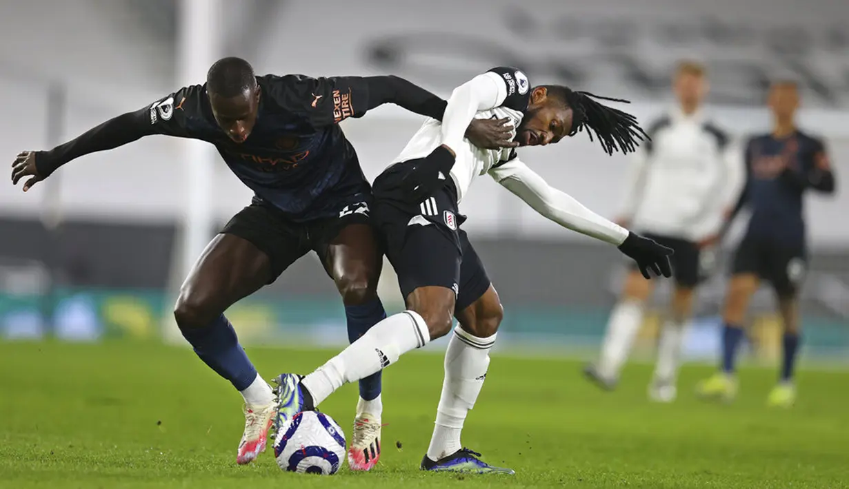 Pemain Manchester City Benjamin Mendy (kiri) memperebutkan bola dengan pemain Fulham Andre-Frank Zambo Anguissa pada pertandingan Liga Inggris di Stadion Craven Cottage, London, Inggris, Sabtu (13/3/2021). Manchester City menang 3-0. (Catherine Ivill/Pool via AP)