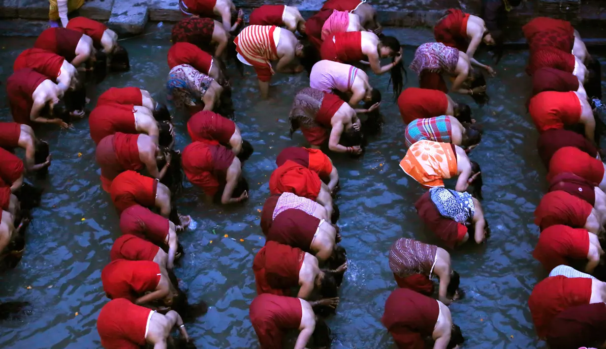 Sejumlah wanita Hindu Nepal merendam rambut dan tubuh mereka di Sungai Bagmati saat upacara Madhav Narayan di Kathmandu, Nepal (27/1). Mereka juga memohon diberikan umur yang panjang. (AP Photo/Niranjan Shrestha)