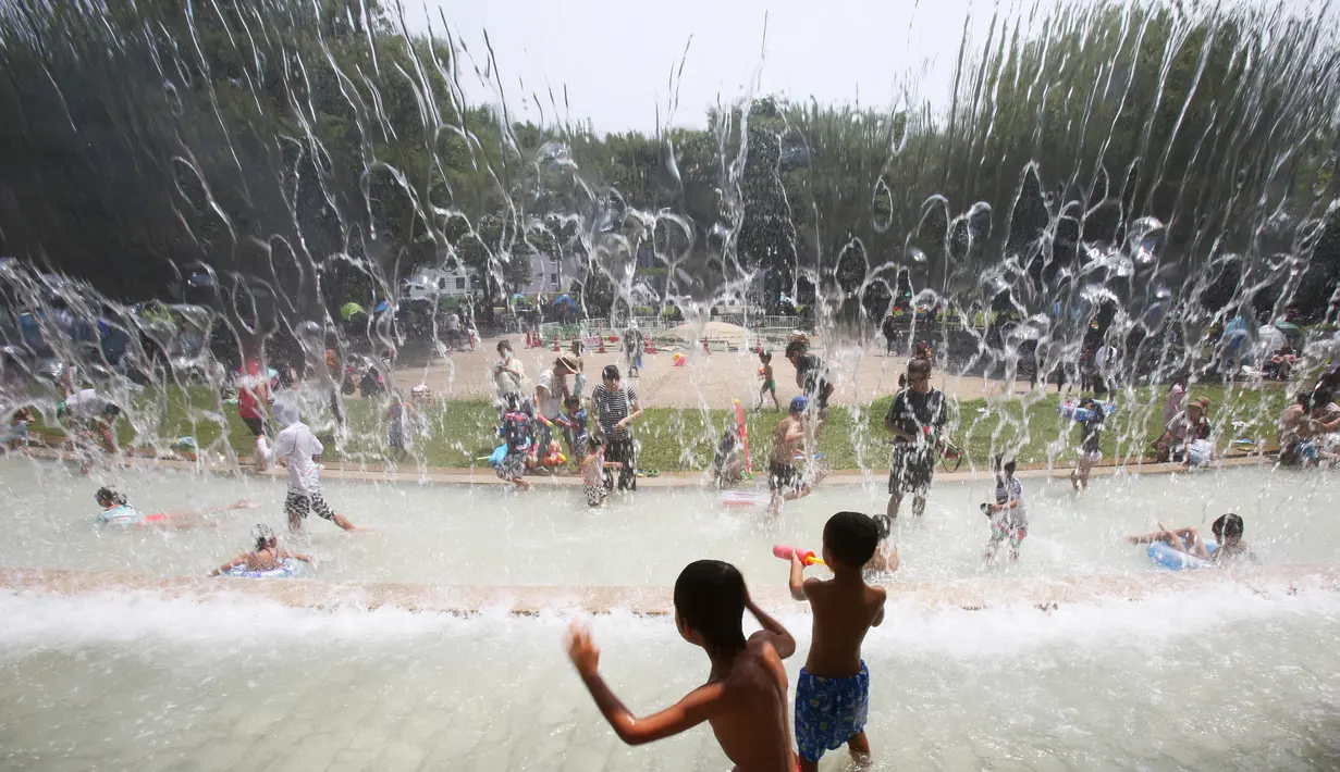 Anak-anak bermain di air di sebuah taman di Tokyo, Jepang, (16/7). Badan Meteorologi mengatakan gelombang panas terus berlanjut di wilayah metro ketika suhu naik mencapai 35 derajat Celcius (95 derajat Fahrenheit). (AP Photo/Koji Sasahara)