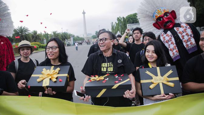 Aktivis yang tergabung dalam Amnesty Internasional Indonesia membawa bingkisan untuk pemerintah saat menggelar aksi di depan Istana Negara, Jakarta, Selasa (10/12/2019). Momen pemberian bingkisan untuk pemerintah dinamakan Aksi Penyerahan Pesan Perubahan (PENA). (Liputan6.com/Faizal Fanani)