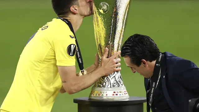 Penyerang Villarreal, Gerard Moreno, mencium trofi Liga Europa di depan pelatihnya, Unai Emery, setelah mengalahkan Manchester United di Stadion Stadion Miejski, Gdansk, Polandia, Kamis (25/7/2021) dini hari WIB.