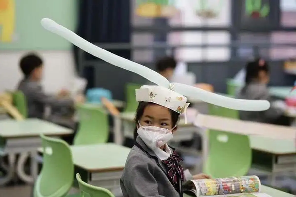 Para murid yang kembali bersekolah di China mengenakan topi yang menjaga jarak mereka antar satu dengan yang lainnya.