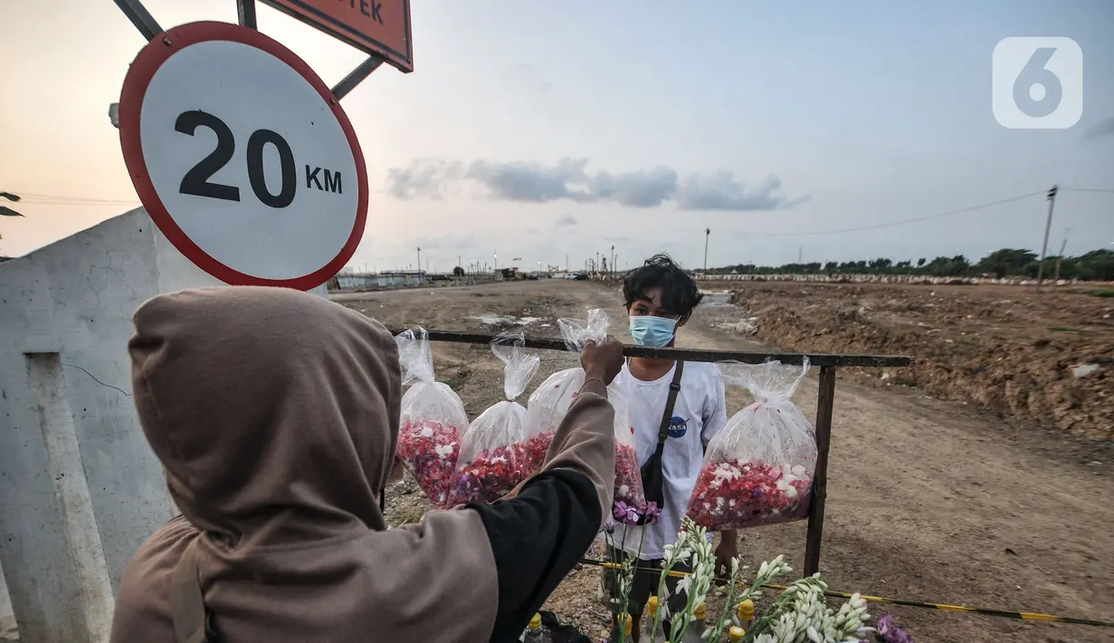 Pedagang saat melayani peziarah yang membeli bunga di TPU Rorotan, Jakarta, Selasa (10/8/2021). Rusdi (30) salah satu pedagang menungkapkan lapak bunga ziarah mulai ramai bermunculan didirikan warga setempat di depan TPU Rorotan sejak dua bulan lalu. (merdeka.com/Iqbal S. Nugroho)