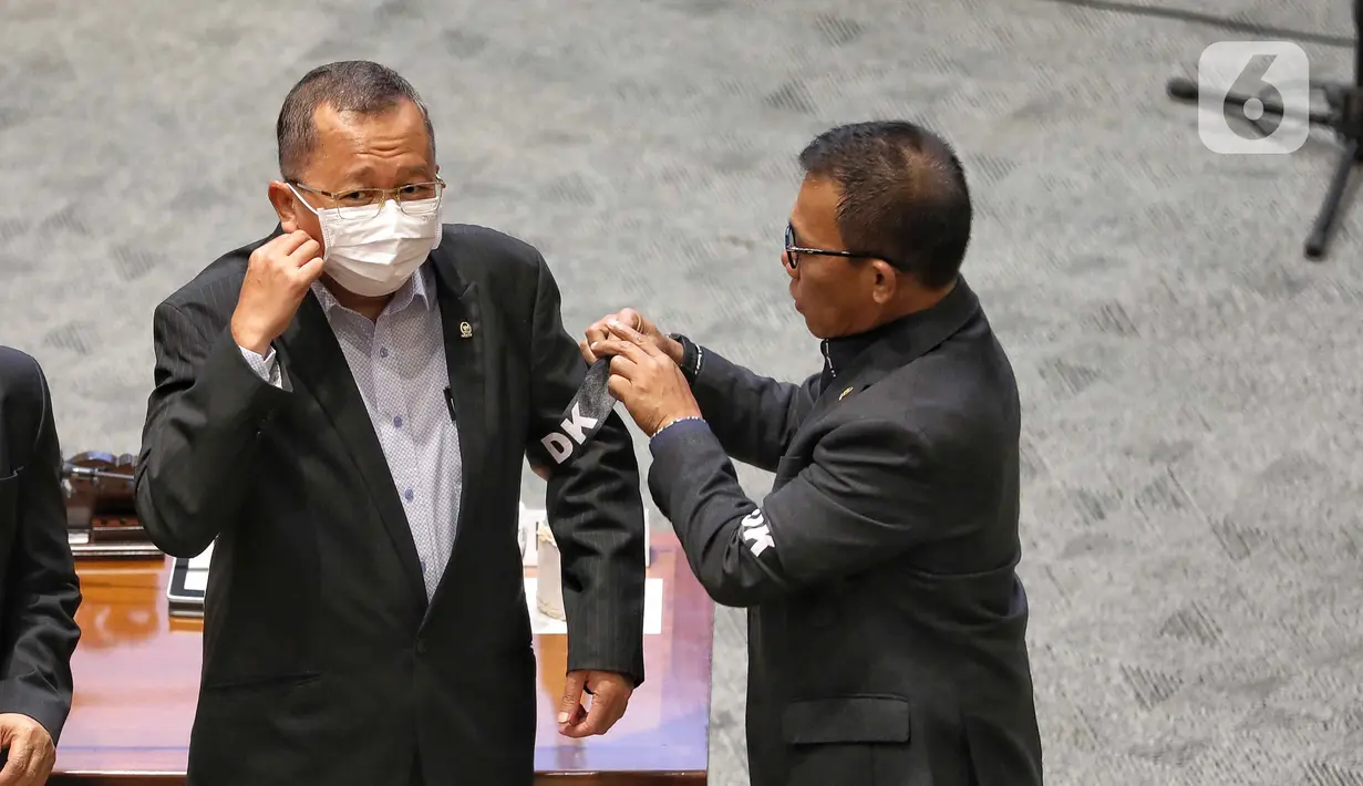 Anggota DPR Memasangkan pita hitam bertuliskan DK di lengan saat rapat Paripurna DPR Ke-8 Masa Persidangan I Tahun Sidang 2022-2023 di Kompleks Parlemen, Senayan, Jakarta, Selasa (4/10/2022). Rapat juga memutuskan mencabut persetujuan Sudrajad Dimyati sebagai Hakim Agung setelah ditetapkan sebagai tersangka. (Liputan6.com/Angga Yuniar)