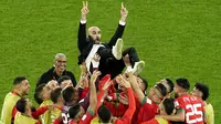 Para pemain Maroko mengangkat pelatih Walid Regragui saat merayakan kemenangan atas Spanyol pada laga 16 besar Piala Dunia 2022 di Stadion Education City, Selasa (6/12/2022). (AP/Abbie Parr)
