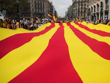 Sejumlah orang mengarak bendera Catalonia raksasa ketika merayakan Hari Nasional Spanyol di jalanan Barcelona, Kamis (12/10). Hari Nasional sendiri memperingati kedatangan pertama Christopher Columbus di Amerika pada tahun 1492. (AP / Santi Palacios)