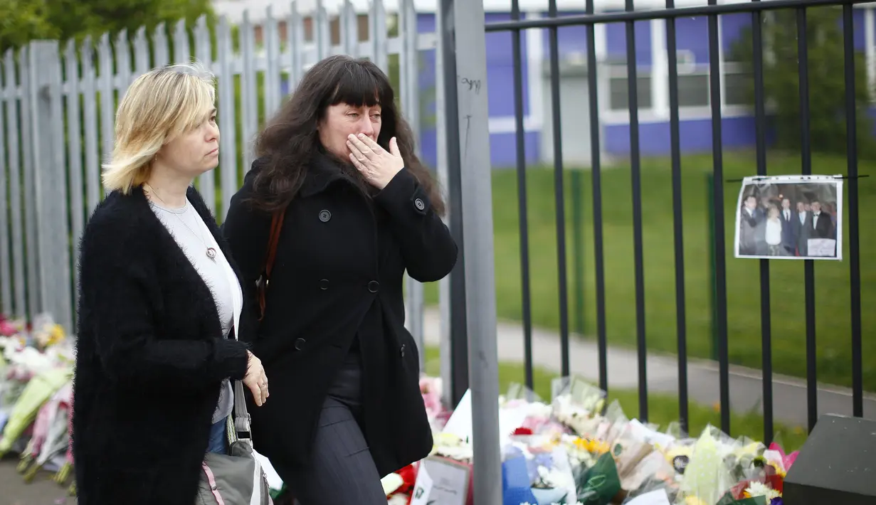 Dua orang guru tak kuasa menahan air matanya saat melintasi karangan bunga untuk Anne Maguire, Leeds, Inggris utara, Selasa (29/04/2014) (Reuters/Darren Staples).