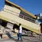 Seorang pria berjalan melewati bangunan yang runtuh akibat gempa di Reo, provinsi Nusa Tenggara Timur, Indonesia, Senin, 17 Agustus 2026. (AP Photo/Firdia Lisnawati)