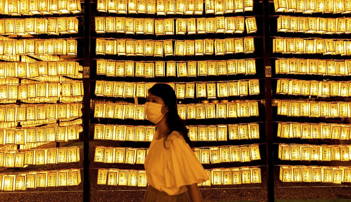 Pengunjung berjalan melewati lentera kertas saat Festival Mitama di Kuil Yasukuni, Tokyo, Jepang, Rabu (14/7/2021). Festival Mitama dirayakan sejak 1947 untuk menghormati jiwa para arwah yang diabadikan serta tentara yang gugur dari perang Jepang di masa lalu. (BEHROUZ MEHRI/AFP)