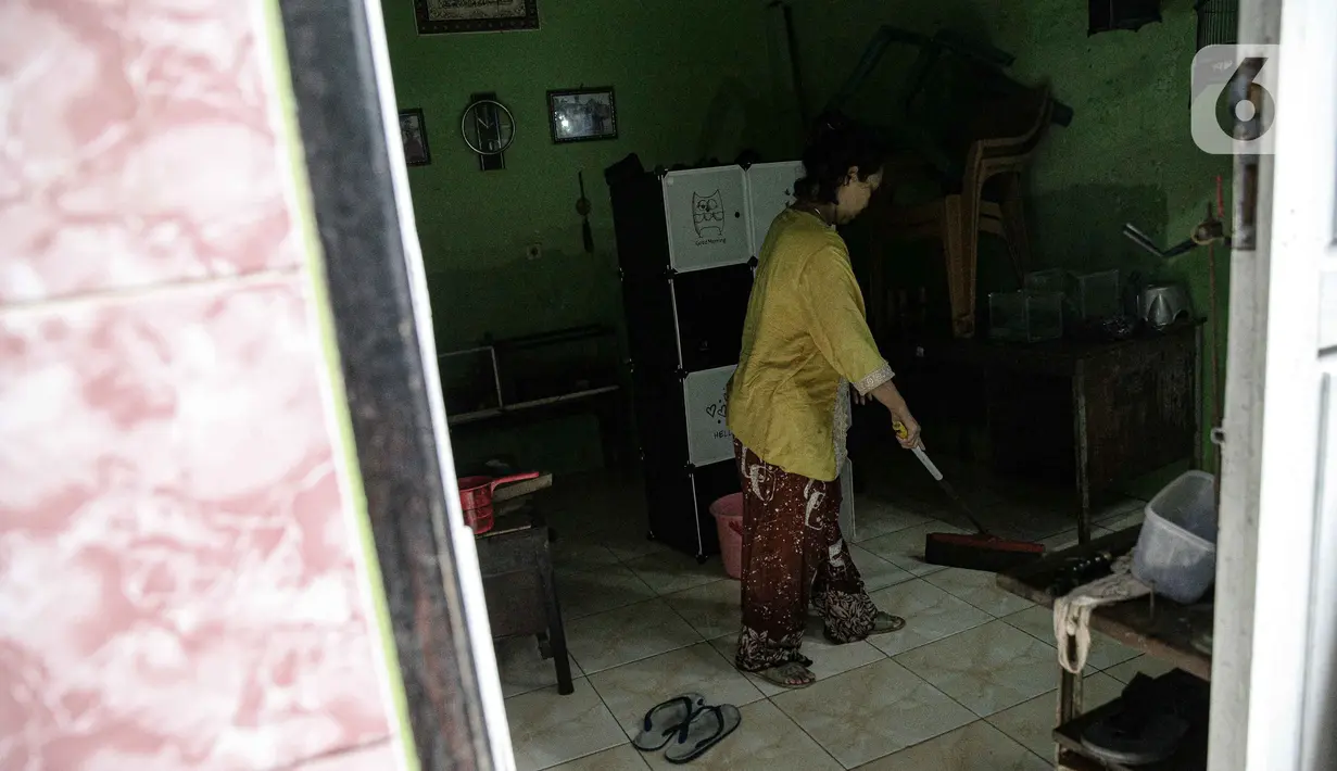Warga bersih-bersih rumah usai terendam banjir di kawasan Kampung Melayu, Jakarta, Senin (8/11/2021). Banjir akibat luapan Kali Ciliwung tersebut merendam pemukiman setinggi 60 cm sejak 7 November 2021 sore. (Liputan6.com/Faizal Fanani)