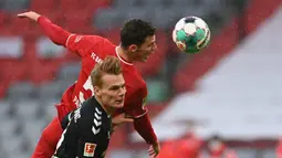 Bek Freiburg, Philipp Leinhart (depan) berebut bola dengan bek Bayern Munich, Benjamin Pavard dalam laga lanjutan Liga Jerman 2020/21 pekan ke-16 di Allianz Arena, Minggu (17/1/2021). Freiburg kalah 1-2 dari Bayern Munich. (AFP/Christof Stache/Pool)