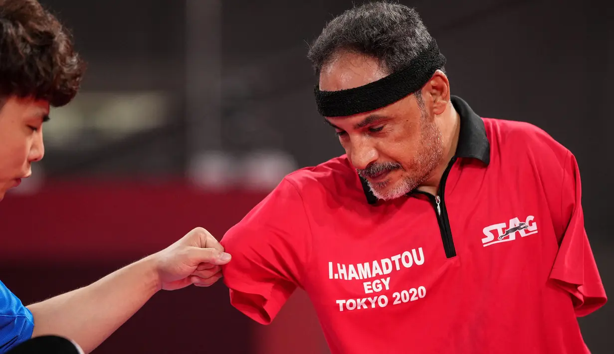 Atlet para-tenis meja Mesir, Ibrahim Elhusseiny Hamadtou berjabat tangan dengan Chao Chen dari China setelah pertandingan Group E kelas 6 Tenis Meja Putra Paralimpiade Tokyo 2020 di Tokyo Metropolitan Gymnasium, Jumat (27/8/2021). (Yasuyoshi CHIBA / AFP)