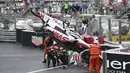 Sejumlah marshall berusaha mengevakuasi mobil pembalap Haas, Mick Schumacher usai mengalami kecelakaan saat Formula 1 GP Monako yang berlangsung di Circuit de Monaco, Minggu, 29 Mei 2022. (AP/Pool/Christian Bruna)