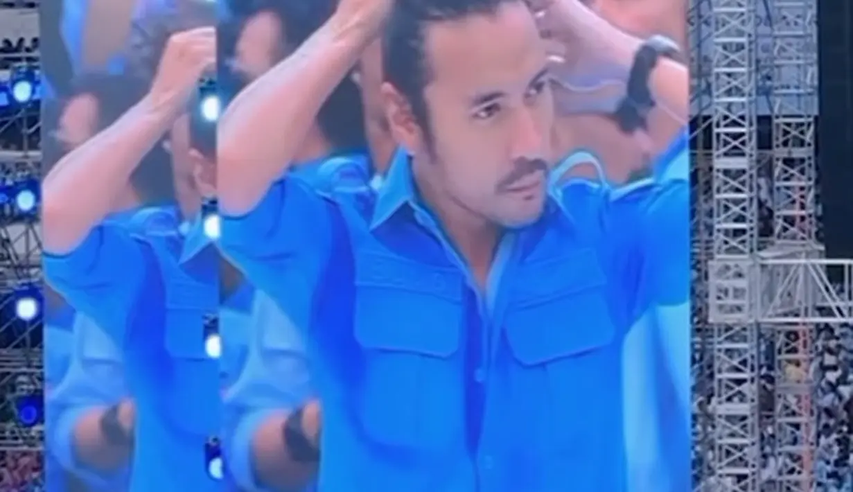 Di sebuah acara, di atas panggung, Ello terlihat disorot kamera dan muncul di layar super besar sedang menguncir rambutnya. [Foto: Instagram/marcellover_tahitoe]