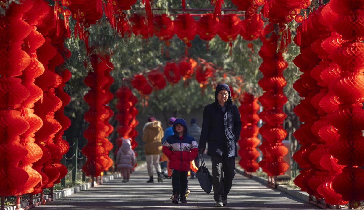<p>Seorang pria dan anak laki-laki berjalan di sepanjang jalan yang dihiasi lentera untuk Tahun Baru Imlek mendatang di sebuah taman umum di Beijing, Jumat, 20 Januari 2023. Tahun Kelinci secara resmi dimulai pada 22 Januari. (AP Photo/Mark Schiefelbein)</p>