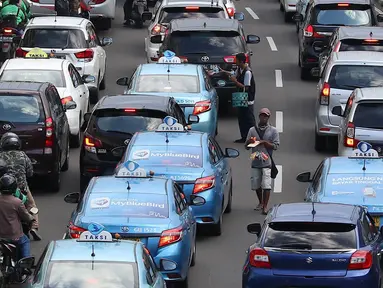 Pedagang asongan menjajakan barang dagangannya di persimpangan lampu merah di Jakarta, Jumat (22/2). Keahlian yang terbatas menyebabkan sebagian orang harus bekerja di tengah padatnya kendaraan Ibukota. (Liputan6.com/Immanuel Antonius)