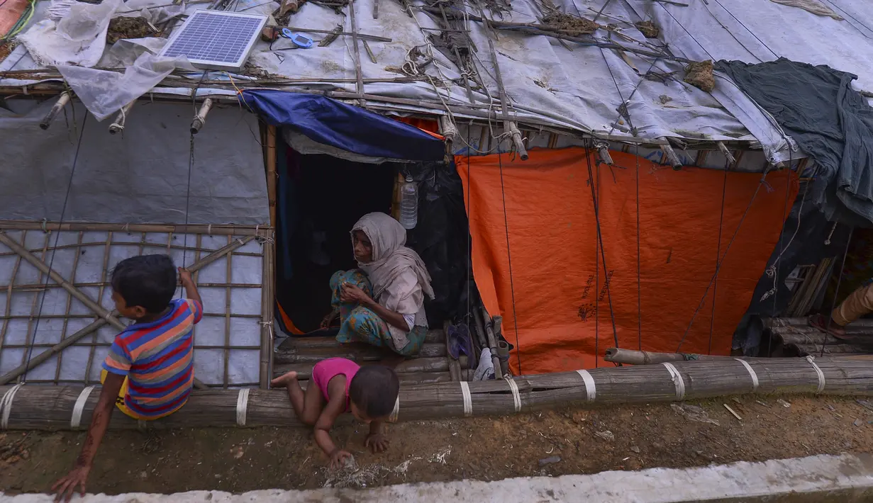 Anak-anak Rohingya bermain di depan rumah darurat di Kamp Pengungsi Kutupalong di Cox's Bazar, Bangladesh, Senin (22/7/2019). Lebih dari satu juta etnis Rohingya melarikan diri dari Myanmar dan menetap di Kutupalong yang merupakan salah satu kamp pengungsi terbesar di dunia. (MUNIR UZ ZAMAN/AFP)