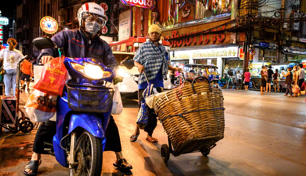 Seorang pengantar barang mendorong gerobaknya di sebuah jalan di Chinatown Bangkok (16/9/2020). Di Chinatown Bangkok terdapat juga beberapa kuil penting, salah satunya Wat Traimit yang ada di ujung jalan Yao Warat. (AFP/Mladen Antonov)