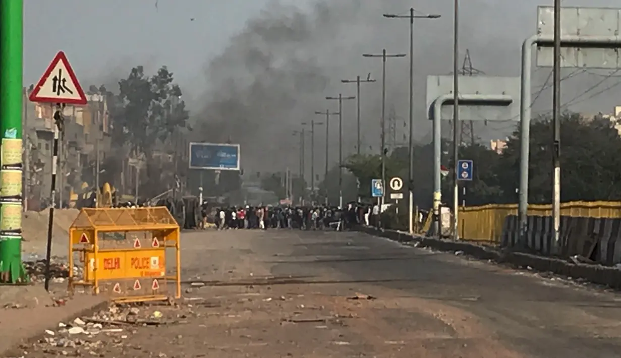 Asap membumbung saat bentrok massa pendukung dan penentang Undang-Undang Kewarganegaraan baru di New Delhi, India, Selasa (25/2/2020). UU Kewarganegaraan baru memudahkan nonmuslim dari tiga negara tetangga, yang didominasi muslim, untuk mendapatkan kewarganegaraan India. (AP Photo/Rishabh. R. Jain)