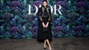 Karlie Kloss tampil anggun dengan koleksi Dior Cruise 2023. Ia mengenakan jaket wol hitam embroideri dengan kemeja silk hitam dan rok wol hitam. [Dior]