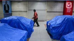Pengunjung melintas depan departemen store yang masih tutup di pusat perbelanjaan ITC BSD Serpong, Tangerang Selatan, Selasa (16/6/2020). Sejumlah tenant dan kios masih tutup selama PSBB Tangerang Raya diperpanjang hingga 28 Juni karena penambahan kasus positif Covid-19. (Liputan6.com/Fery Pradolo)