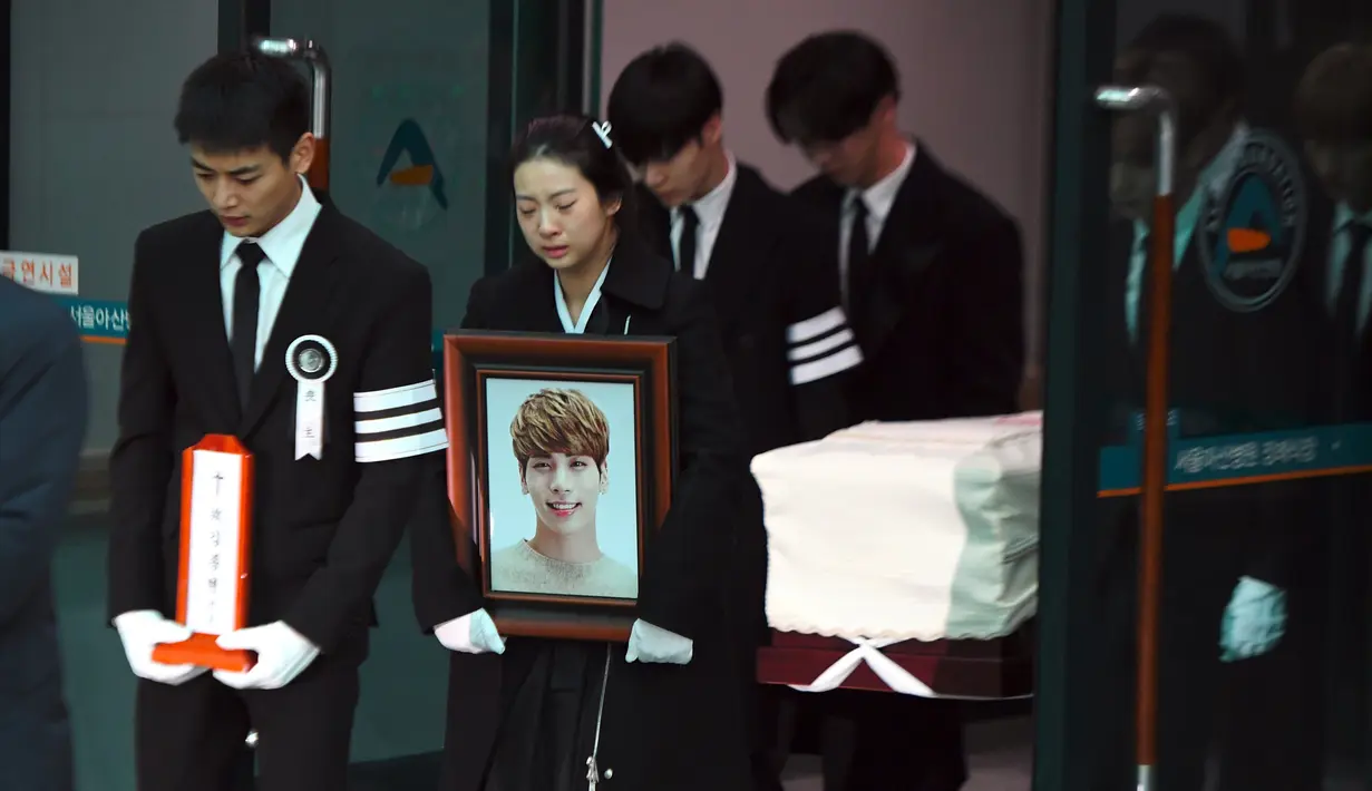 Minho (kiri) membawa plakat pada prosesi pelepasan jenazah Jonghyun SHINee menuju tempat pemakaman dari Asan Hospital, Seoul, Kamis (21/12). Minho berusaha tegar saat memimpin iringan bersama kakak Jonghyun yang membawa foto sang adik. (JUNG Yeon-Je/AFP)