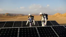 Astronot analog Israel berjalan di antara panel surya saat melakukan simulasi kehidupan di Planet Mars di Gurun Negev, Minggu (18/2).  Lokasi tersebut dipilih karena diklaim mirip secara geologi dengan Mars. (MENAHEM KAHANA/AFP)