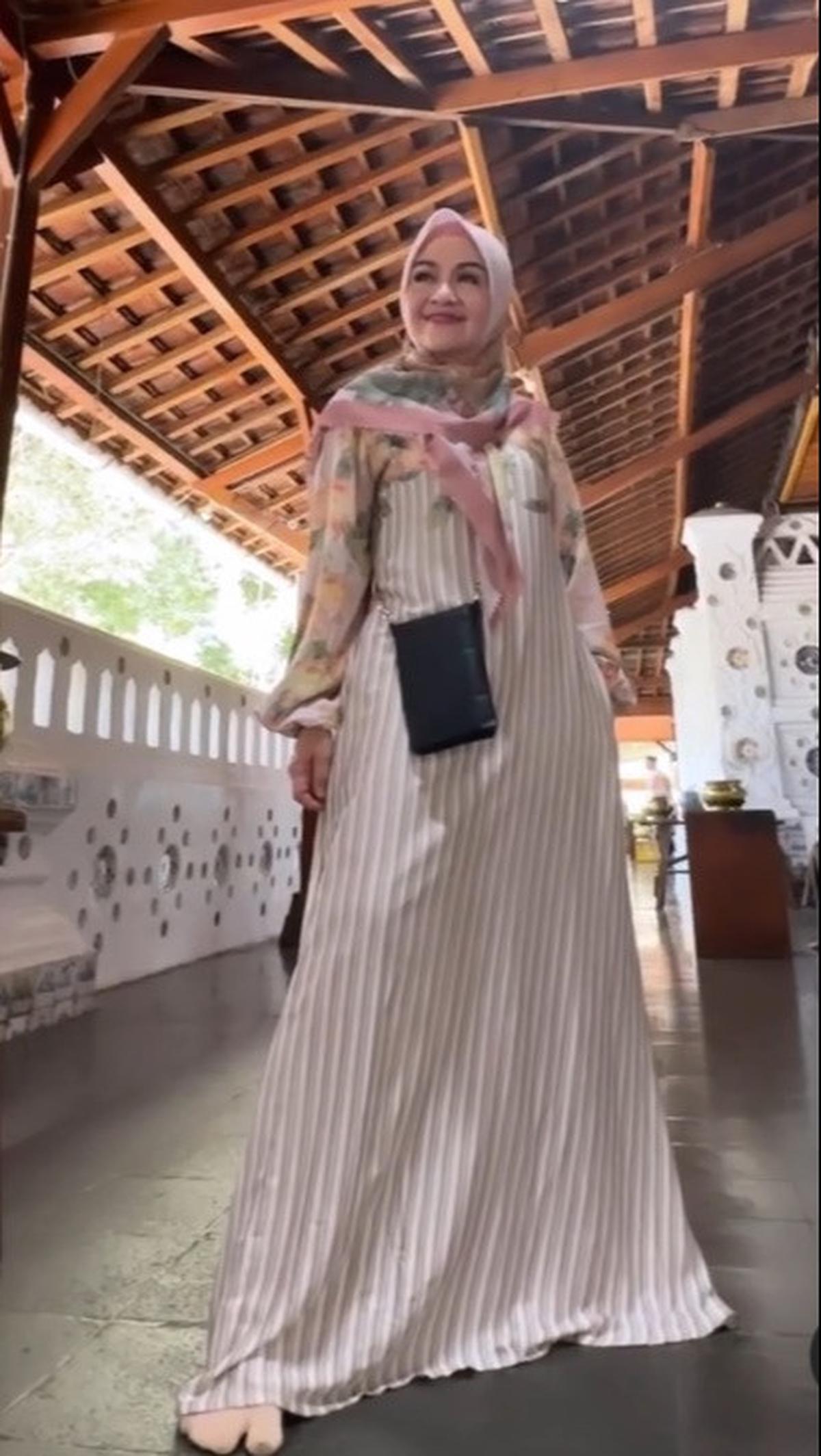 Jika ingin lebih kalem, gamis berwarna pastel bisa dipadukan dengan jilbab bunga-bunga berwarna lembut. Gaya Lulu satu ini terlihat simple namun tetap chic berkat tambahan mini slingbag berwarna hitam.