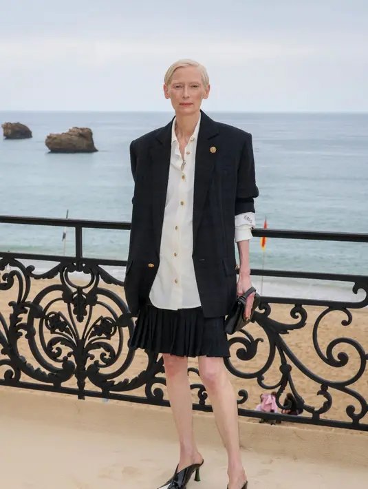  jaket suede beige dipadu kemeja merah bold dan celana tailored, dilengkapi tas Chanel pink statement yang playful sekaligus sentimental. [Dok/Chanel].