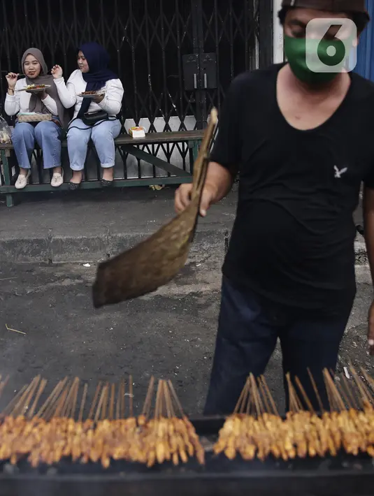 Pemebeli makan satai yang dijual PKL di kawasan Pasar Lama Tangerang, Banten, Sabtu (18/9/2021). Menko Perekonomian Airlangga Hartarto mengatakan Presiden Joko Widodo akan meluncurkan program Bantuan Langsung Tunai (BLT) untuk 1,2 juta PKL dan pemilik warteg. (Liputan6.com/Angga Yuniar)