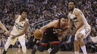 Guard Toronto Raptors Fred VanVleet (tengah) menerobos pertahanan Milwaukee Bucks pada lanjutan NBA 2017-2018 di Air Canada Centre, Jumat (23/2/2018) atau Sabtu (24/2/2018) WIB. (Chris Young/The Canadian Press via AP)
